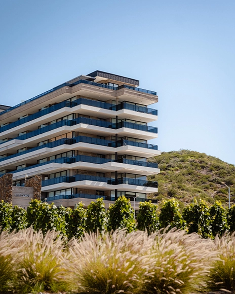 Edificio residencial con balcones y un jardín de pastos ornamentales