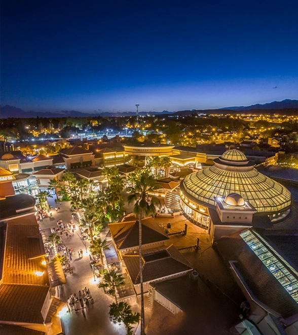 Vista aérea nocturna de un paseo comercial con una cúpula iluminada