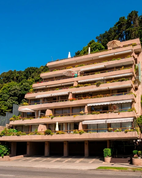 Edificio escalonado con terrazas y jardines sobre una ladera arbolada